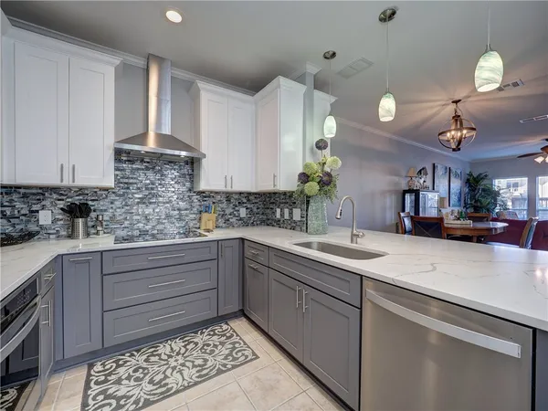 a kitchen with stainless steel appliances granite countertop white cabinets a refrigerator and a stove top oven