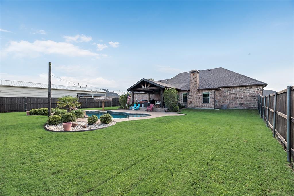 1132 Chartres Street Kaufman, TX 75142 - Photo 21 of 25 Expansive backyard featuring a gunite pool, a covered patio with exposed beams, and a brick-faced exterior