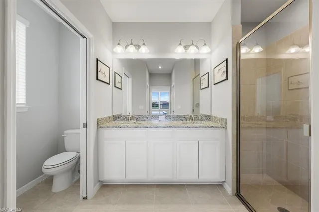 a bathroom with a granite countertop sink a toilet a mirror and shower