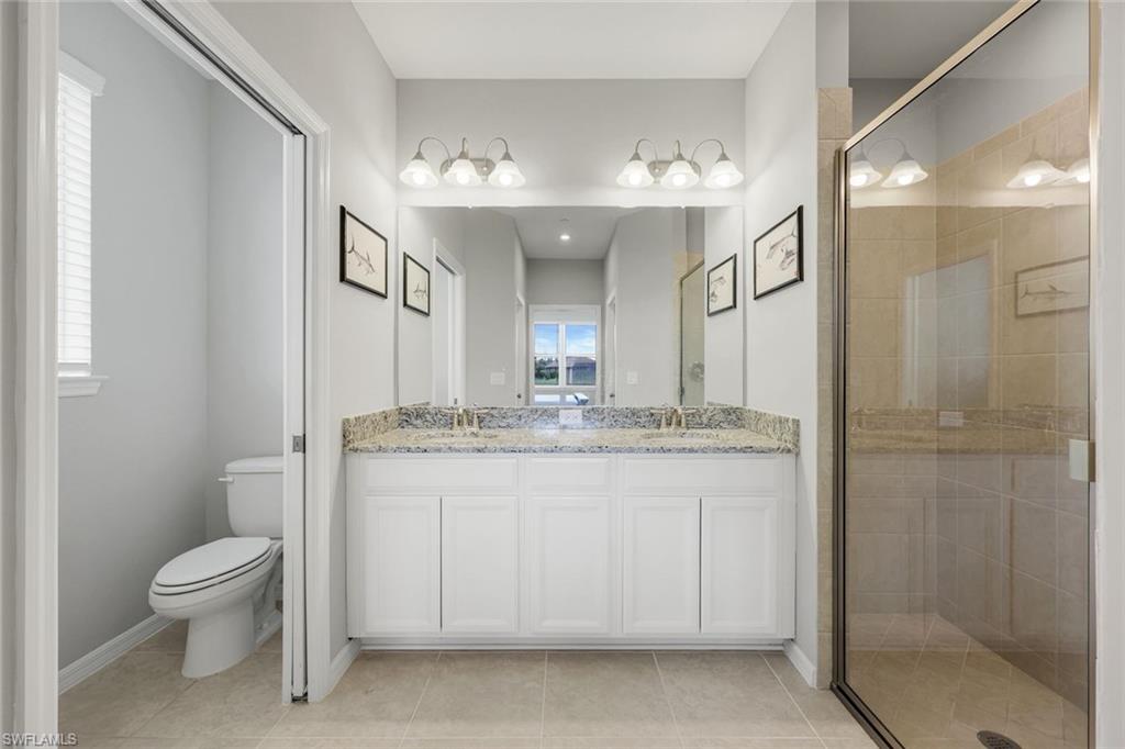 9393 Pocida Court, Unit 104 Naples, FL 34119 - Photo 12 of 28 a bathroom with a granite countertop sink a toilet a mirror and shower