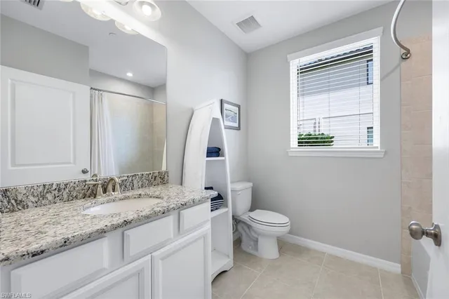 a bathroom with a granite countertop sink toilet and mirror