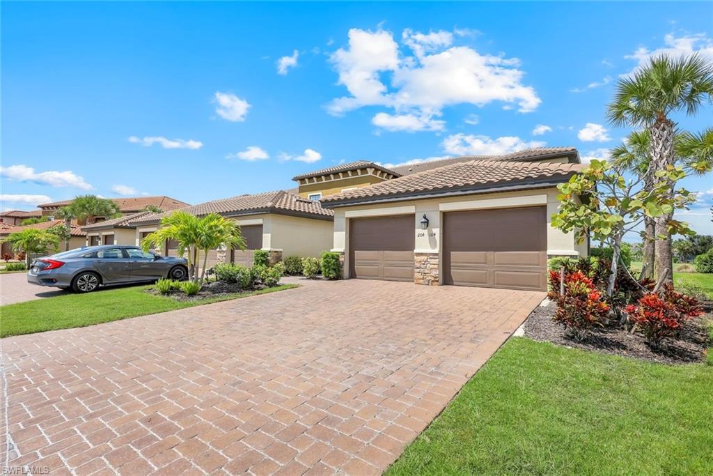 9393 Pocida Court, Unit 104 Naples, FL 34119 - Photo 2 of 28 a front view of a house with a yard and garage