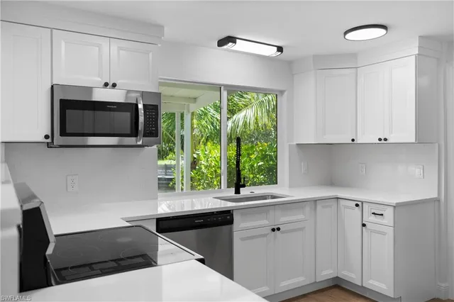 a kitchen with a microwave a stove and white cabinets with wooden floor