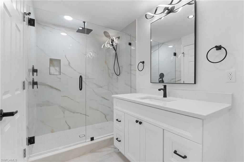66 River Court Naples, FL 34110 - Photo 21 of 29 a bathroom with a shower sink and mirror