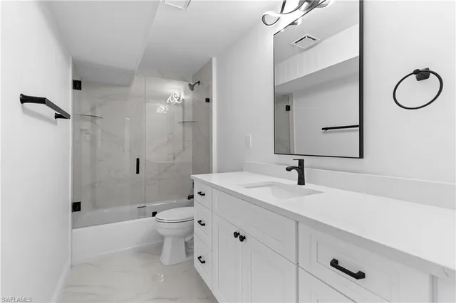 a bathroom with a granite countertop sink a toilet and shower