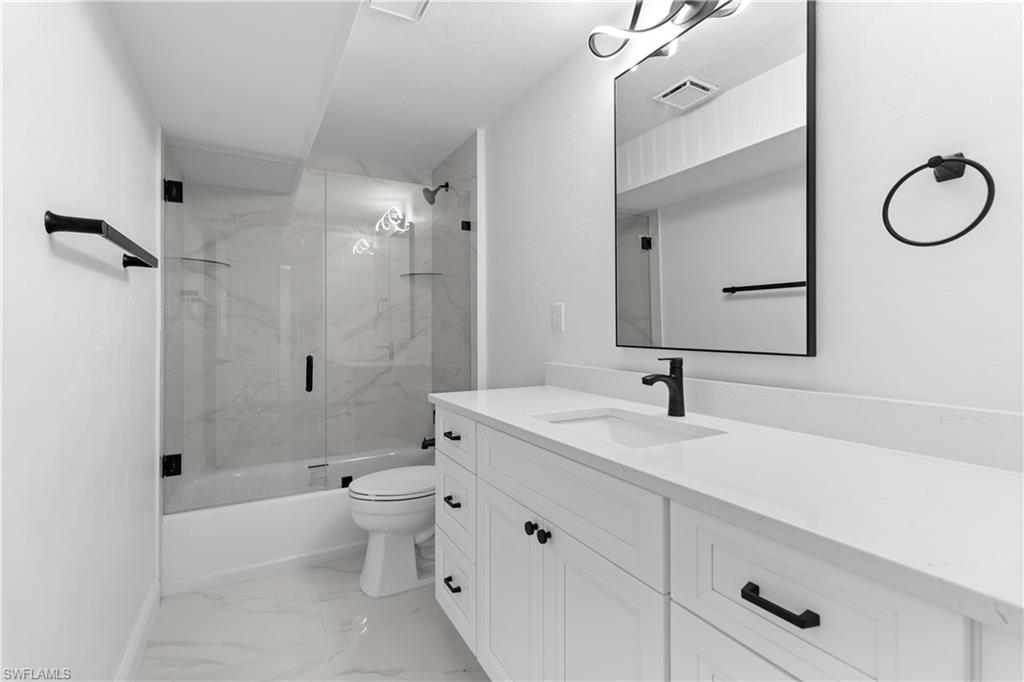 66 River Court Naples, FL 34110 - Photo 24 of 29 a bathroom with a granite countertop sink a toilet and shower
