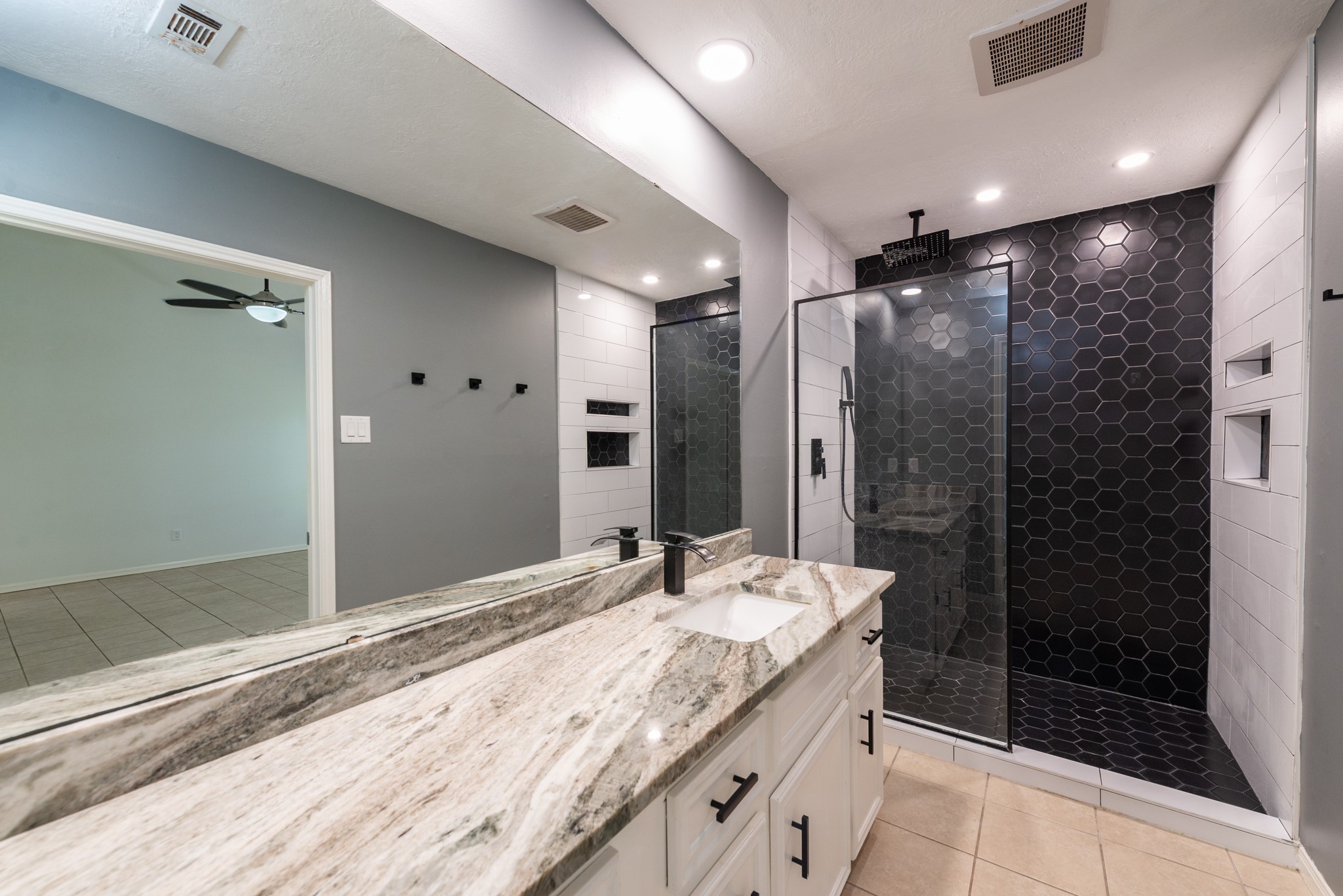 1022 White Sands Road Katy, TX 77450 - Photo 19 of 27 Primary bath with custom walk-in shower showcasing hexagon tiles, waterfall faucet and custom niche cutouts for extra shower storage.