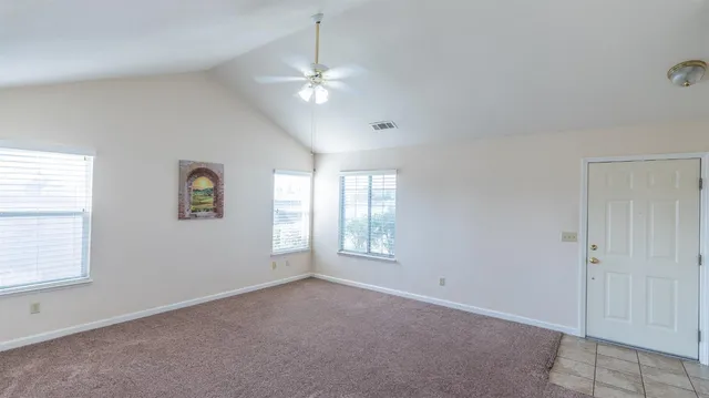 en empty room with windows and chandelier fan