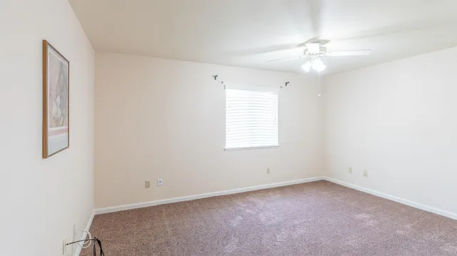 en empty room with windows and chandelier fan