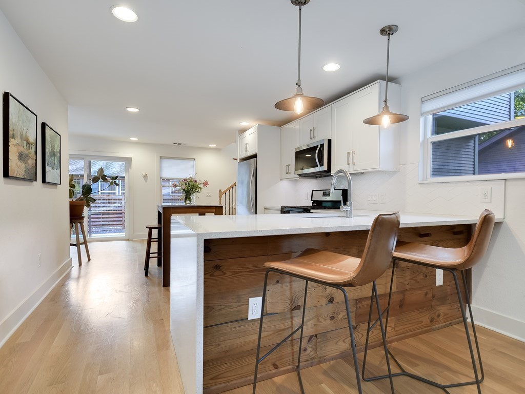 1313 Garden Street Austin, TX 78702 - Photo 7 of 23 a kitchen with kitchen island a dining table chairs stainless steel appliances and cabinets