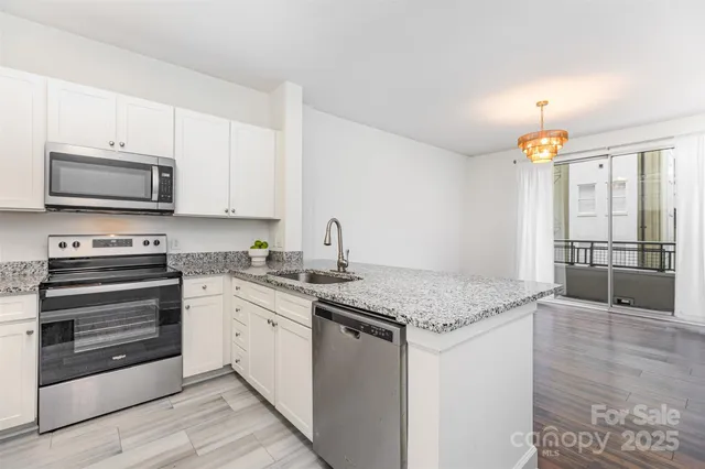 a kitchen with stainless steel appliances granite countertop a stove a sink and a microwave