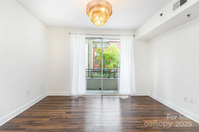 a view of an empty room with wooden floor and window