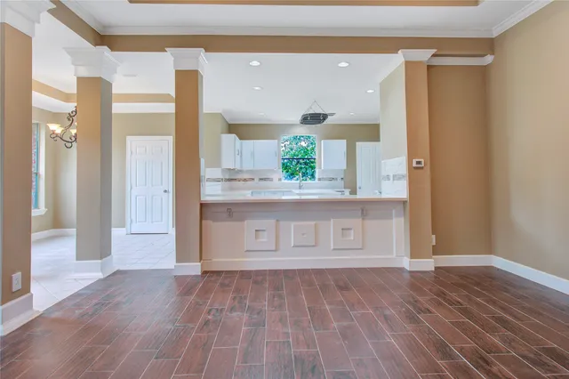 a view of a hallway to a room with wooden floor and cabinet