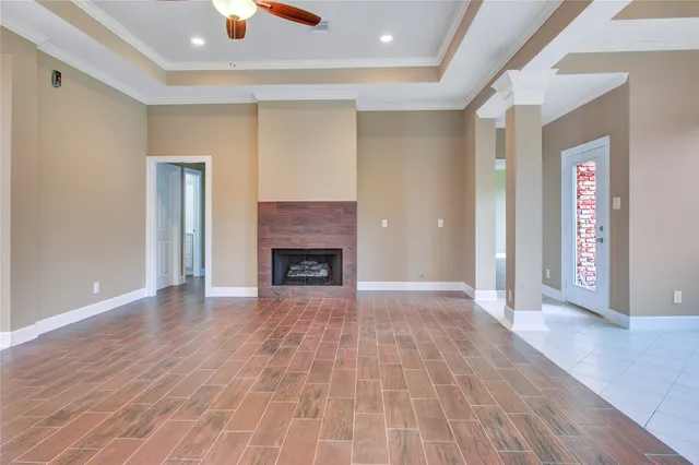 a view of an empty room with wooden floor fireplace and a window