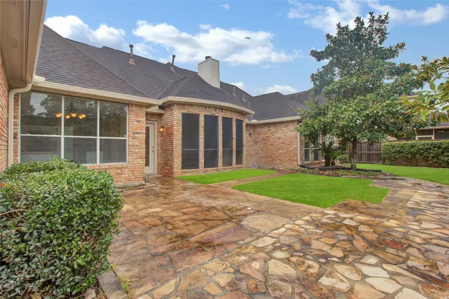a view of a brick house with a yard and large tree
