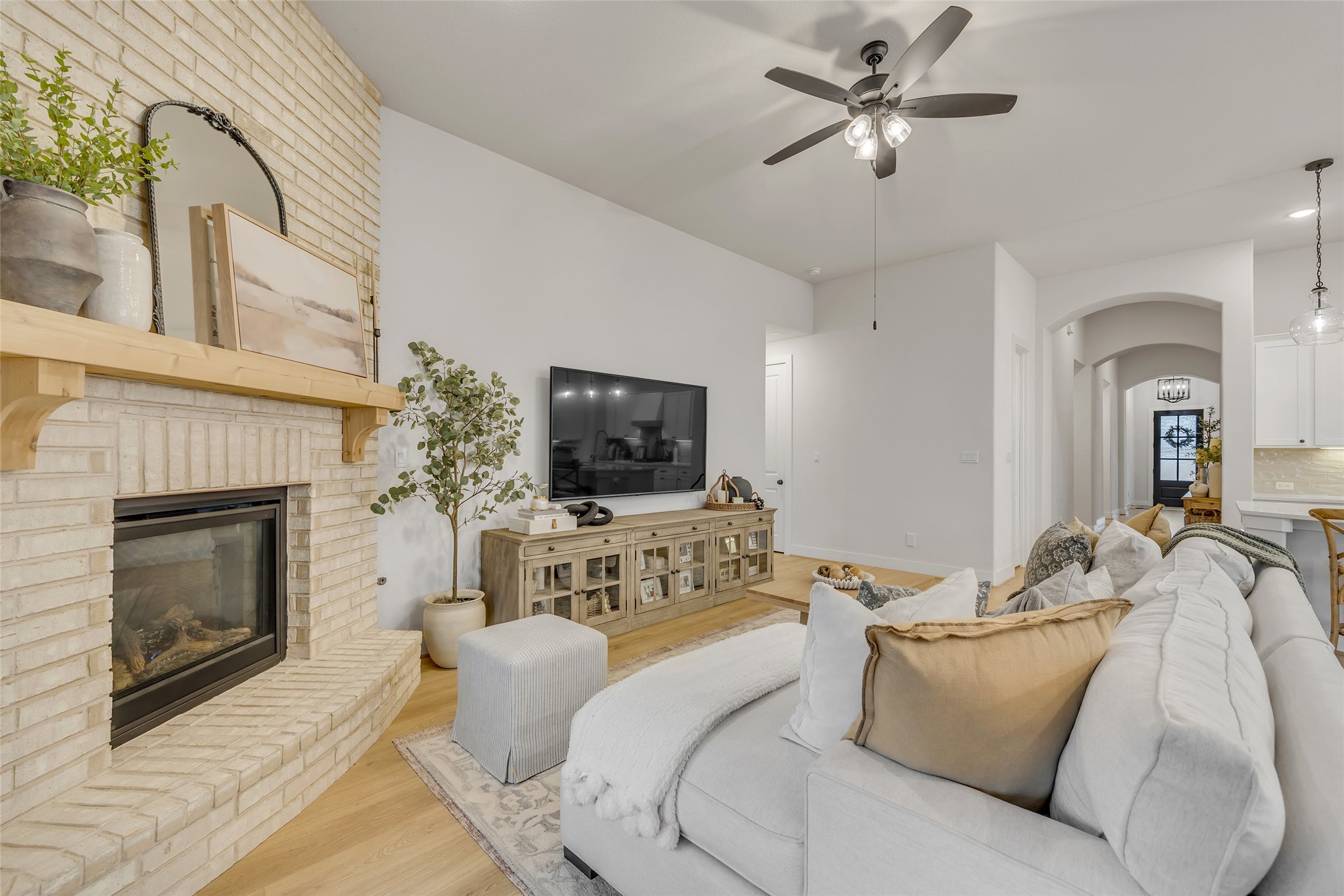 1901 Sir Nathaniel Lane Leander, TX 78641 - Photo 15 of 40 Living room with arched walkways, wood finished floors, a fireplace, and a ceiling fan