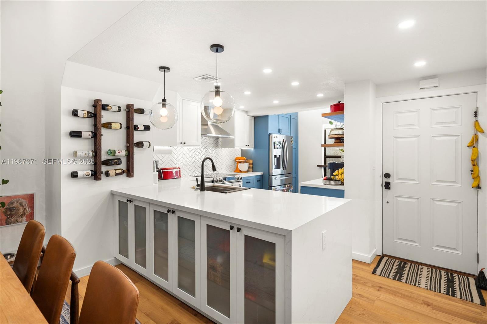 3237 Mary Street, Unit 6 Miami, FL 33133 - Photo 12 of 54 a kitchen with stainless steel appliances kitchen island granite countertop a table chairs in it and wooden floors