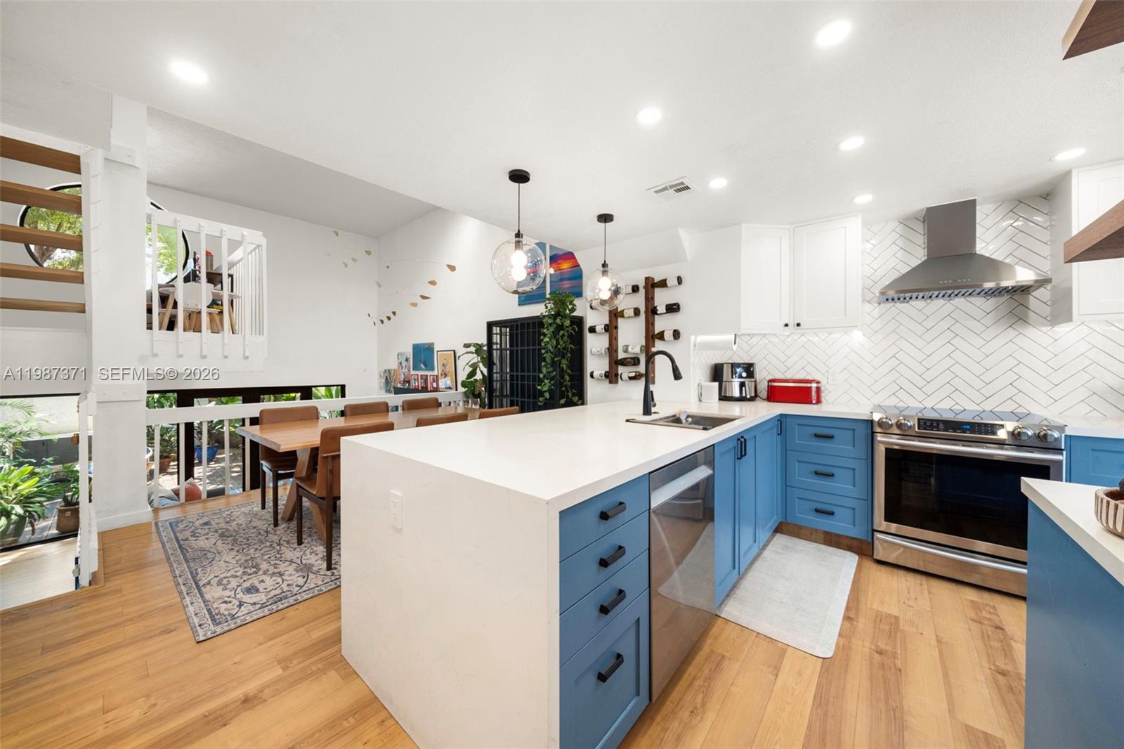 3237 Mary Street, Unit 6 Miami, FL 33133 - Photo 16 of 54 a kitchen with stainless steel appliances kitchen island granite countertop a stove top oven a sink a dining table and chairs with wooden floor