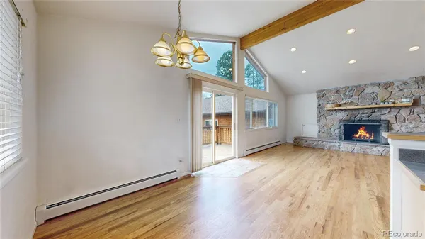 an empty room with wooden floor fireplace and chandelier