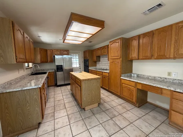 a kitchen with granite countertop a sink a counter top space cabinets and stainless steel appliances