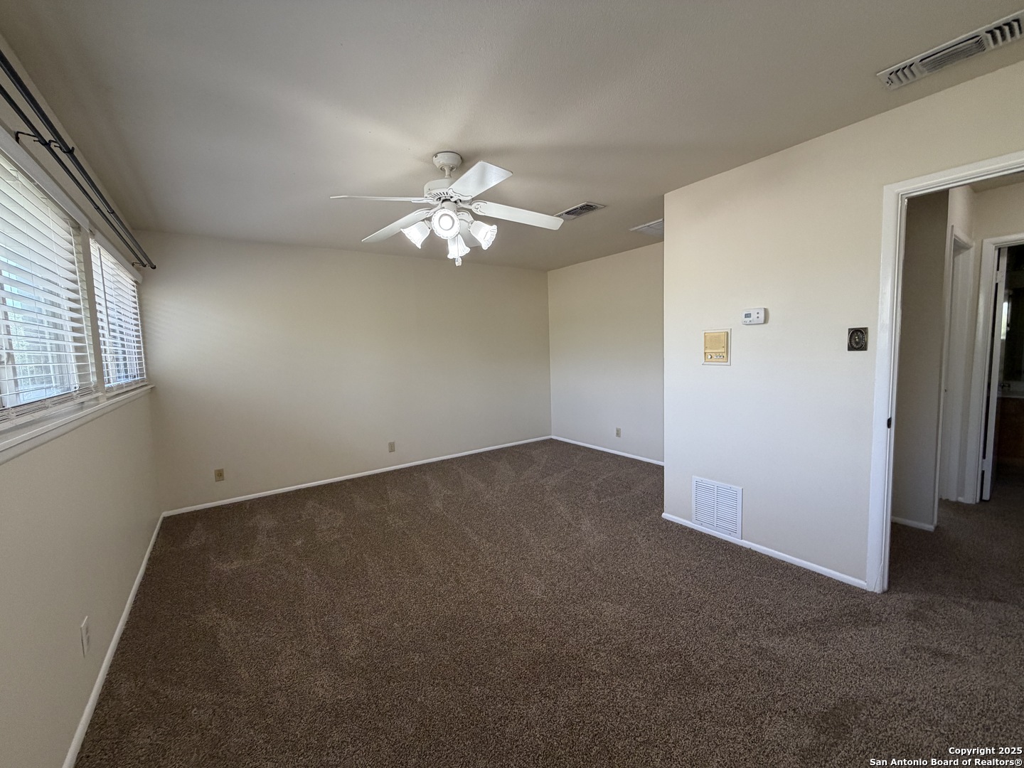 1236 East Live Oak Road Schertz, TX 78154 - Photo 10 of 20 an empty room with a chandelier fan and windows
