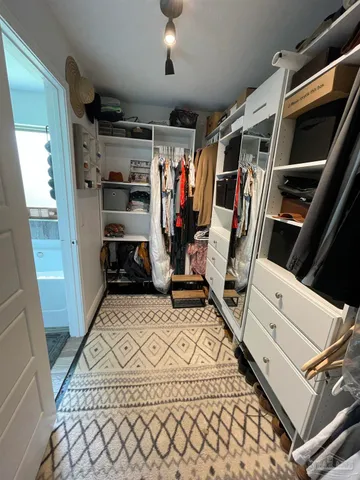 a view of walk in closet with clothes and shoes