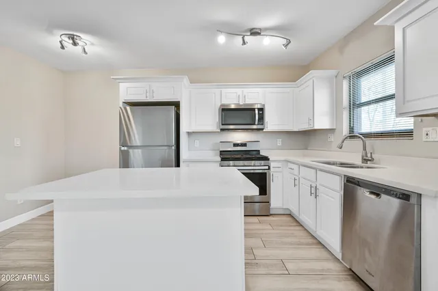 a kitchen with kitchen island a sink stainless steel appliances and cabinets