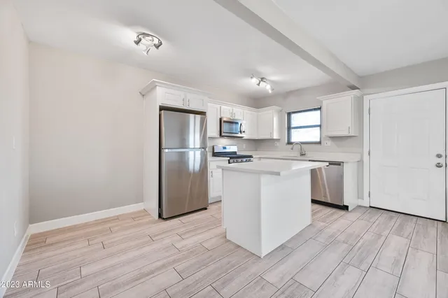 a kitchen with a refrigerator a sink dishwasher with a oven and cabinets with wooden floor