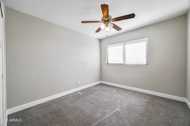an empty room with a window and a ceiling fan