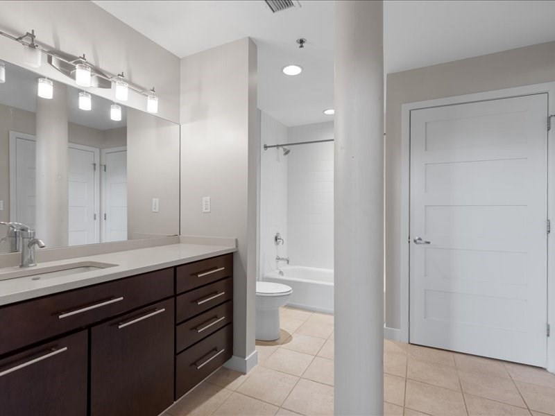 1245 Adams Street, Unit B210 Boston, MA 02124 - Photo 27 of 39 a bathroom with a granite countertop sink a toilet and a large mirror