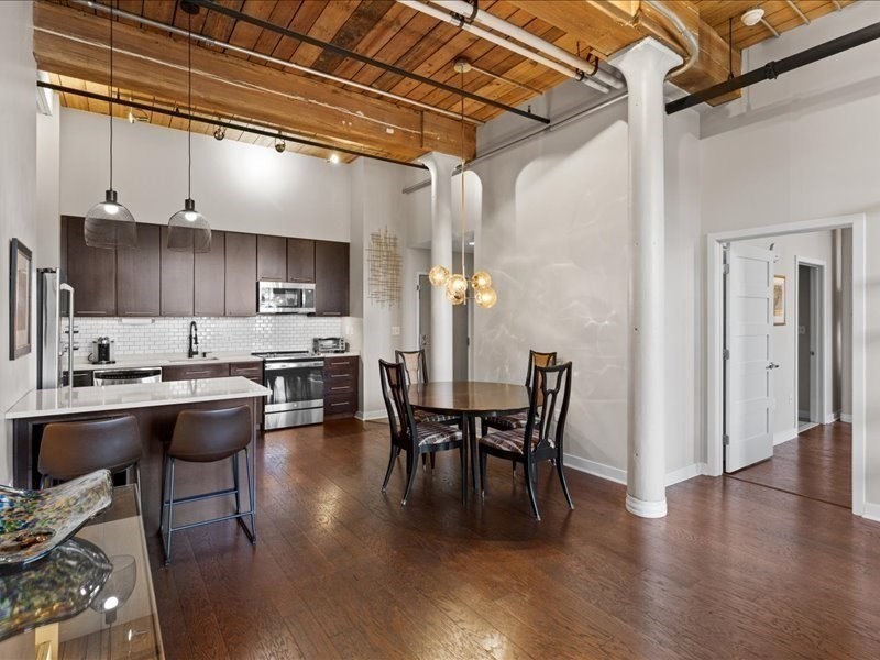 1245 Adams Street, Unit B210 Boston, MA 02124 - Photo 8 of 39 a kitchen with stainless steel appliances granite countertop a table chairs and a wooden floor