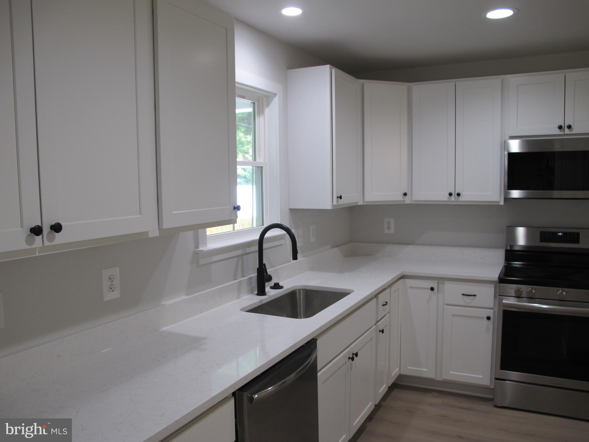 145 9th Street Colonial Beach, VA 22443 - Photo 13 of 51 a kitchen with a sink white cabinets and stainless steel appliances