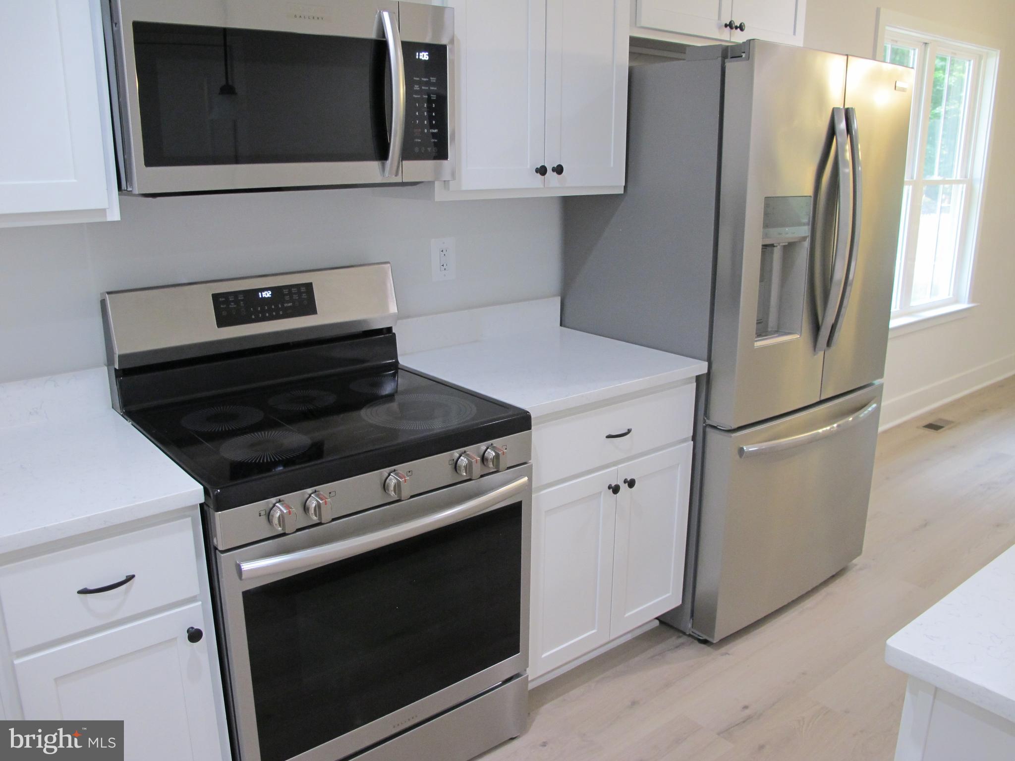 145 9th Street Colonial Beach, VA 22443 - Photo 15 of 51 a kitchen with stainless steel appliances white cabinets white stove a microwave and a refrigerator