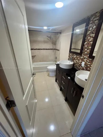 a bathroom with a double vanity sink mirror and toilet