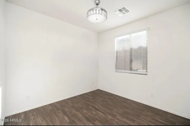 an empty room with wooden floor chandelier fan and windows