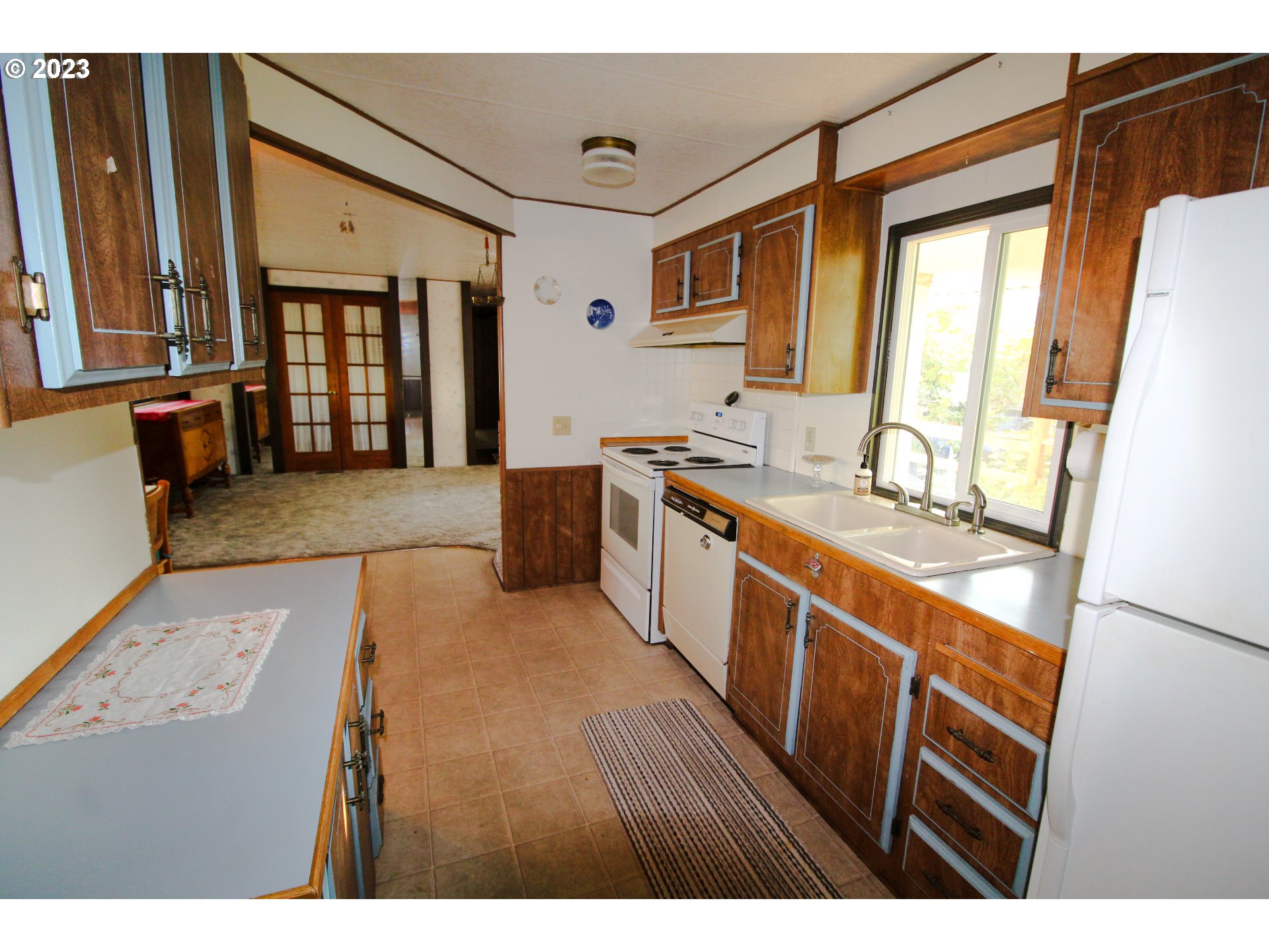 1400 Candlelight Drive, Unit 160 Eugene, OR 97402 - Photo 3 of 31 a large kitchen with kitchen island granite countertop a sink refrigerator and wooden cabinets