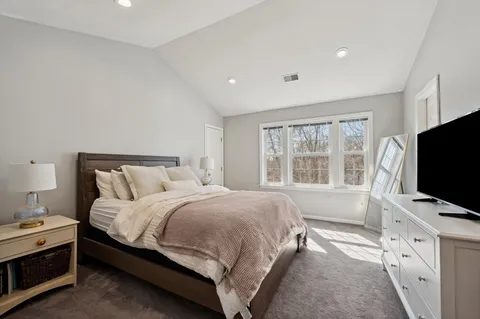 a bedroom with a bed and a flat tv screen on a dresser