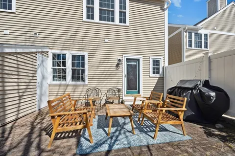 a backyard of a house with wooden chairs