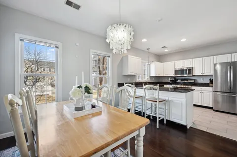 a kitchen with stainless steel appliances a dining table chairs and wooden floor
