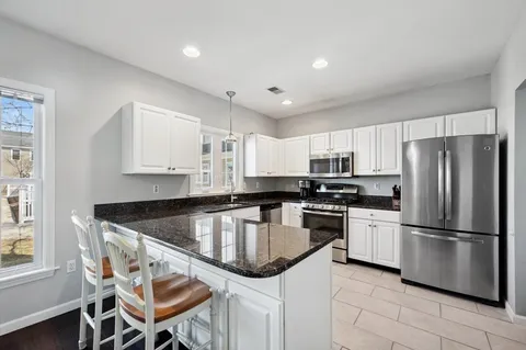 a kitchen with granite countertop stainless steel appliances a refrigerator a stove a sink and chairs