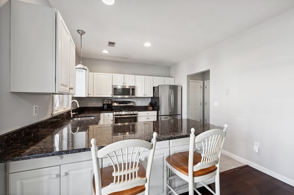 354 Tilden Commons Lane, Unit 354 Braintree, MA 02184 - Photo 8 of 35 a kitchen with stainless steel appliances kitchen island granite countertop a refrigerator and microwave