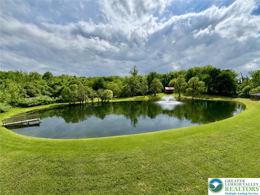 940 Jacktown Road Bangor, PA 18013 - Photo 3 of 33 A tranquil pond with a decorative fountain creates a serene focal point amidst lush green surroundings.