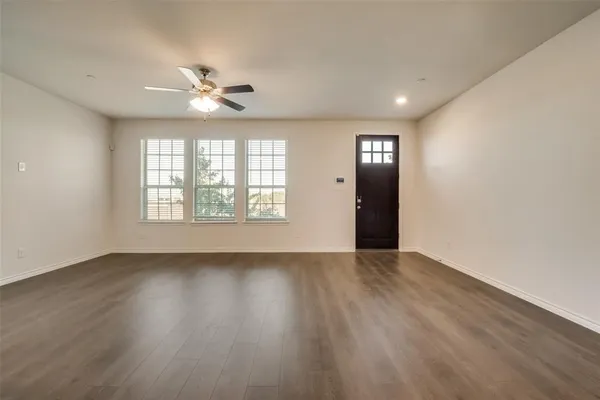 an empty room with wooden floor chandelier and windows