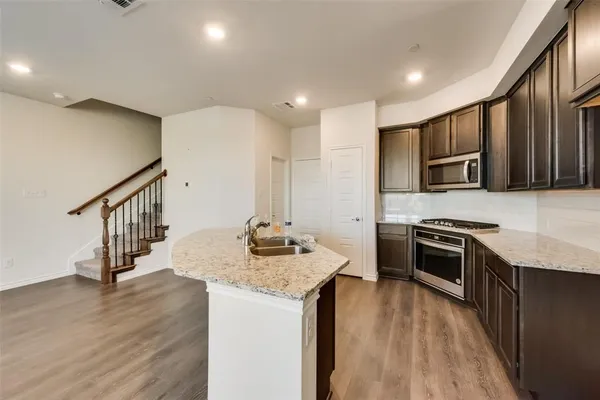 a kitchen with stainless steel appliances granite countertop a sink stove microwave and refrigerator