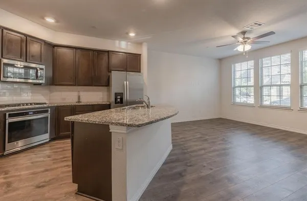 a kitchen with kitchen island granite countertop a sink cabinets and stainless steel appliances