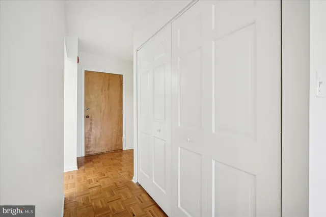 a view of a hallway with wooden floor and closet