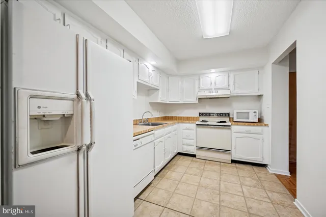 a kitchen with granite countertop a sink stove and refrigerator