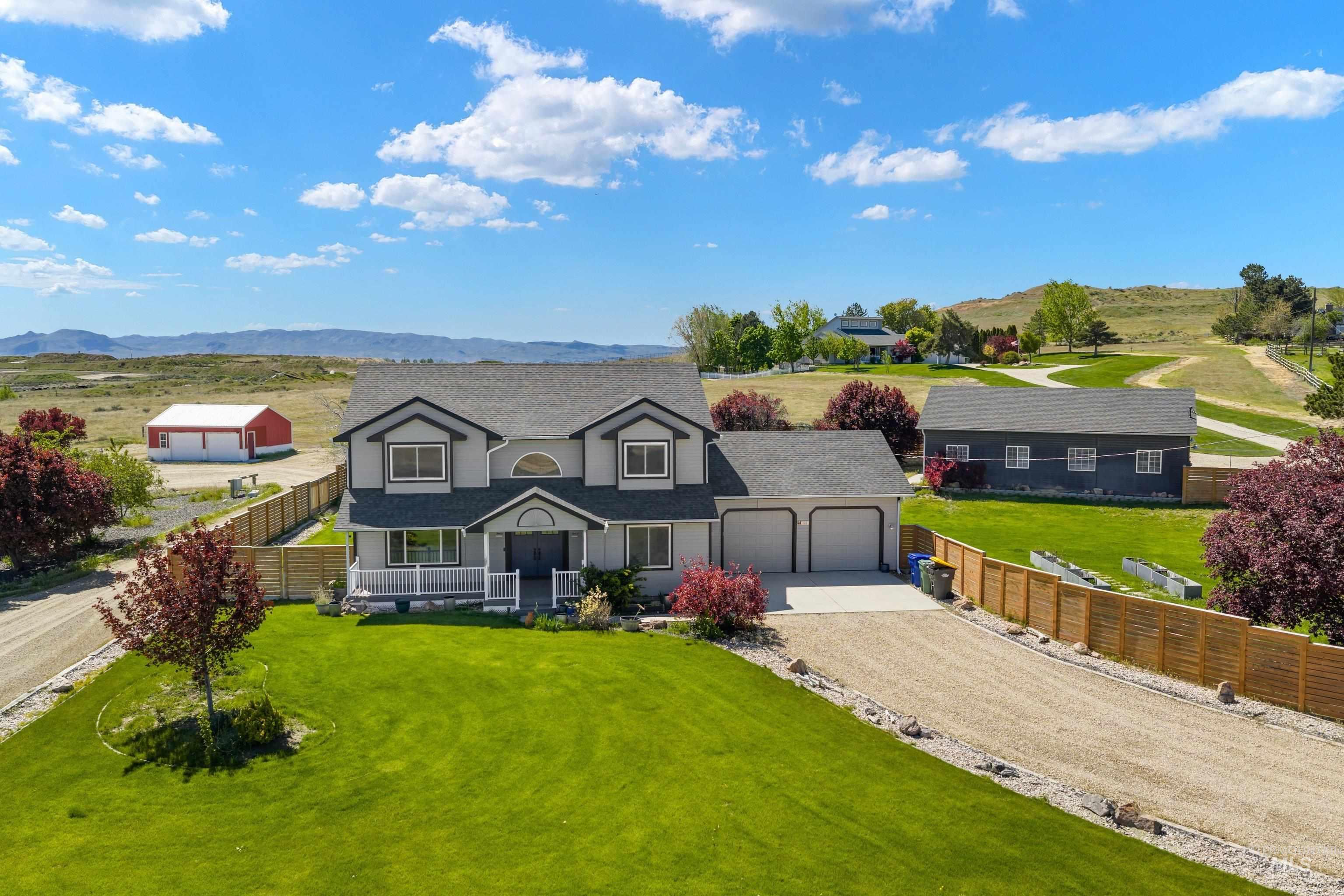 Contemporary two-story residence featuring a two-car garage, expansive green lawn, and mature landscaping