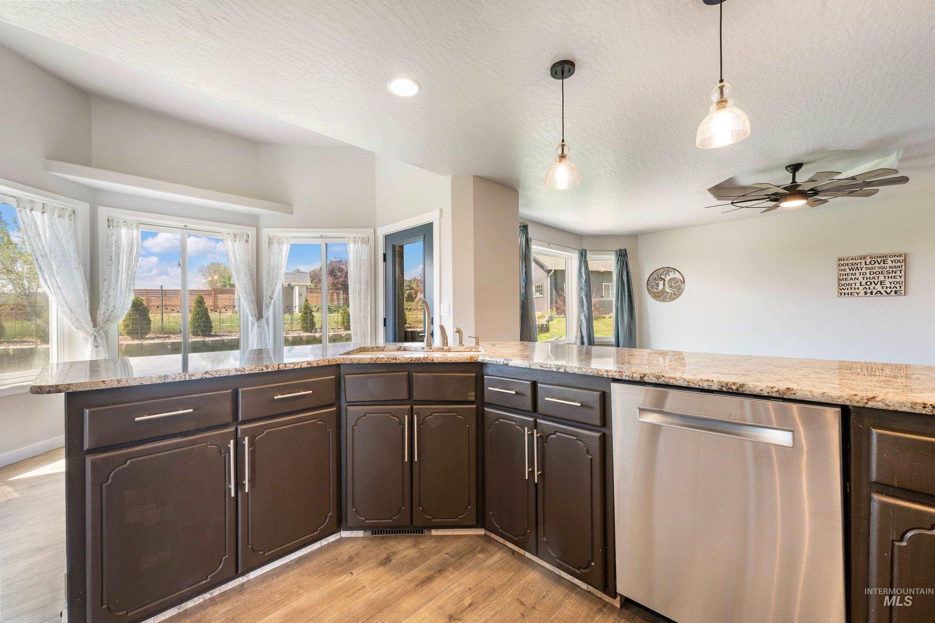 7657 Track Road Nampa, ID 83686 - Photo 11 of 49 Kitchen featuring a peninsula with dark wood-finish cabinetry and light-toned granite countertops