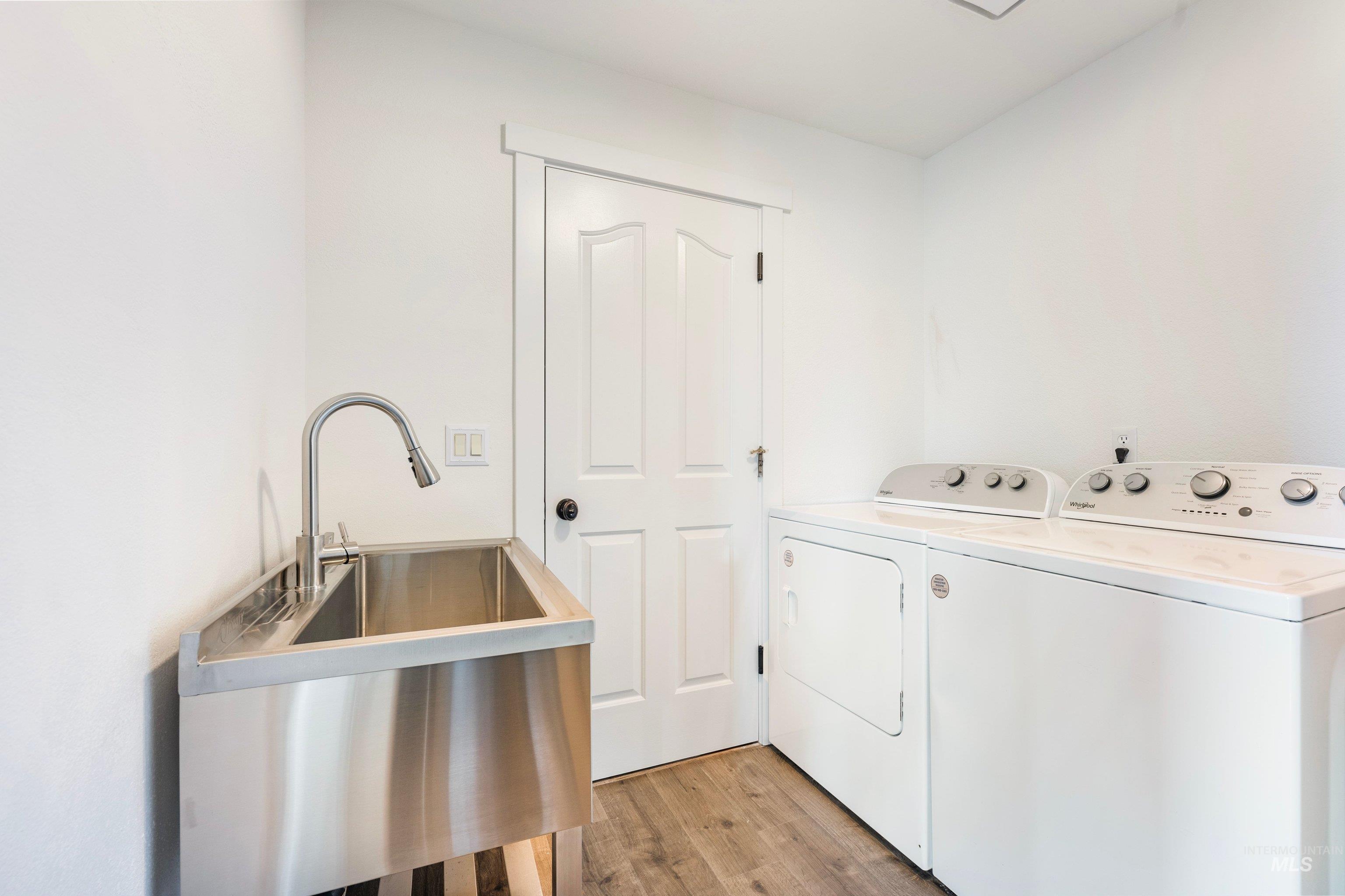7657 Track Road Nampa, ID 83686 - Photo 16 of 49 Utility room featuring a stainless steel sink with a gooseneck faucet, wood-finish flooring, and a white paneled door with dark hardware
